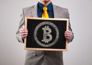 Businessman holding a board with bitcoin symbol and isolated on grey background